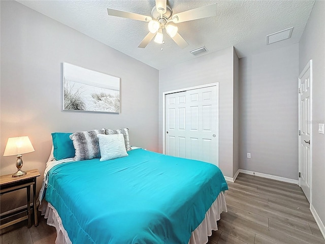 bedroom featuring a closet, visible vents, baseboards, and wood finished floors