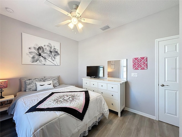 bedroom with visible vents, light wood-style flooring, a ceiling fan, a textured ceiling, and baseboards