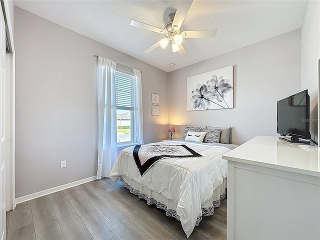 bedroom featuring light wood-style flooring, a textured ceiling, and baseboards