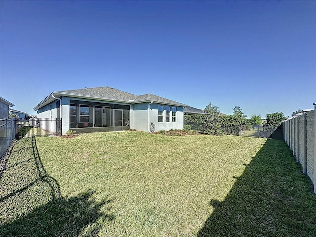 back of property featuring a yard, a fenced backyard, a sunroom, and stucco siding