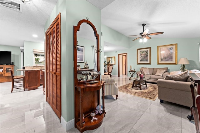 living area with visible vents, marble finish floor, a textured ceiling, and vaulted ceiling