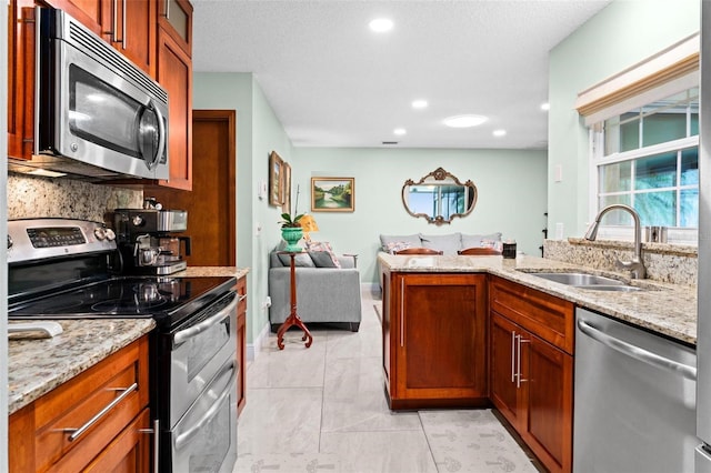 kitchen featuring a sink, stainless steel appliances, light stone countertops, and brown cabinetry