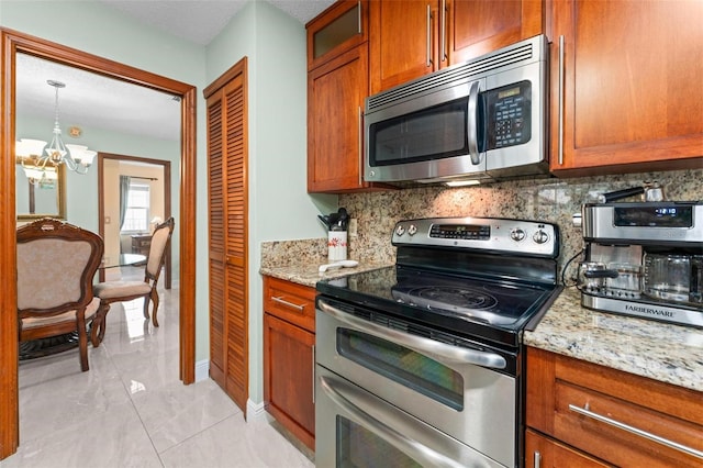 kitchen with decorative backsplash, light stone countertops, brown cabinets, and stainless steel appliances