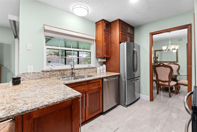 kitchen featuring light stone counters, brown cabinetry, a sink, glass insert cabinets, and appliances with stainless steel finishes