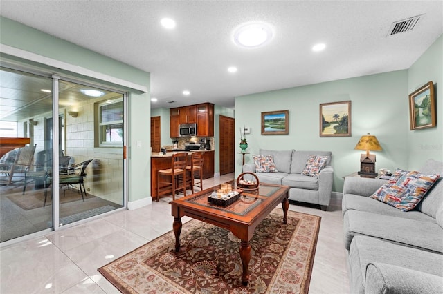 living area featuring recessed lighting, visible vents, baseboards, and a textured ceiling