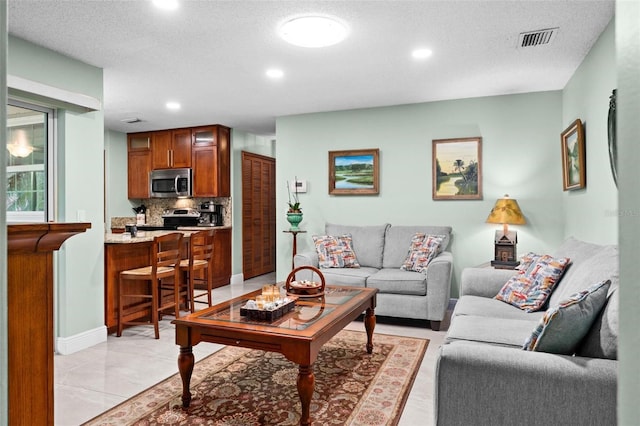 living room with visible vents, recessed lighting, a textured ceiling, and baseboards