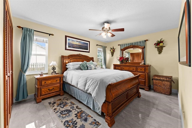 bedroom with ceiling fan, baseboards, and a textured ceiling