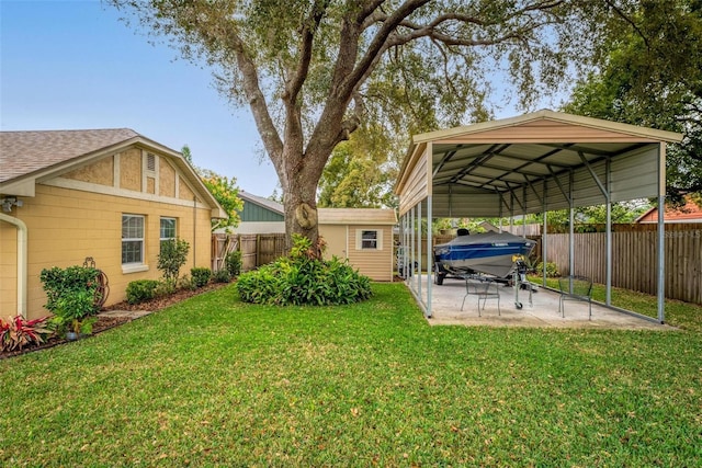 view of yard featuring a detached carport, a patio area, an outbuilding, and a fenced backyard