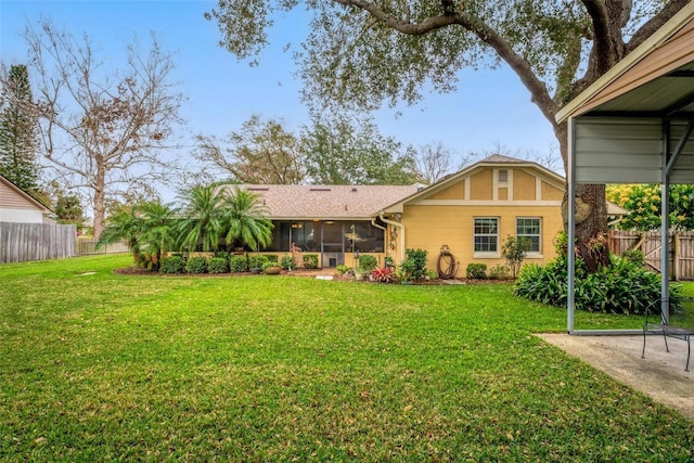 back of property featuring fence, a lawn, and a sunroom