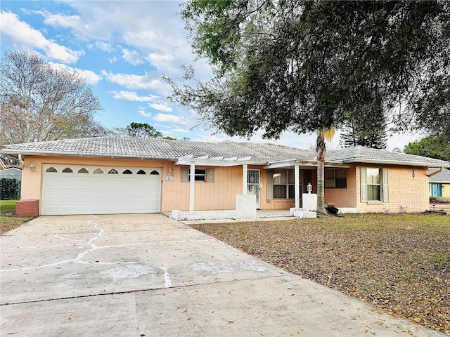 ranch-style home with brick siding, a tile roof, concrete driveway, and a garage