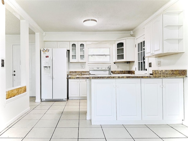 kitchen featuring open shelves, glass insert cabinets, white fridge with ice dispenser, and white cabinetry