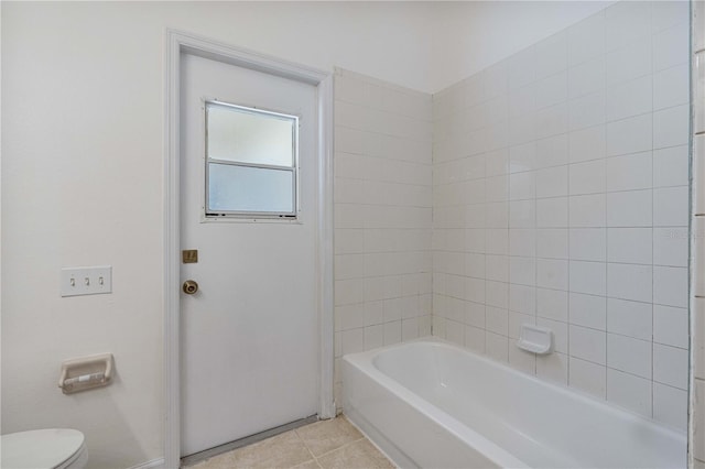 bathroom featuring tile patterned floors, toilet, and bathing tub / shower combination