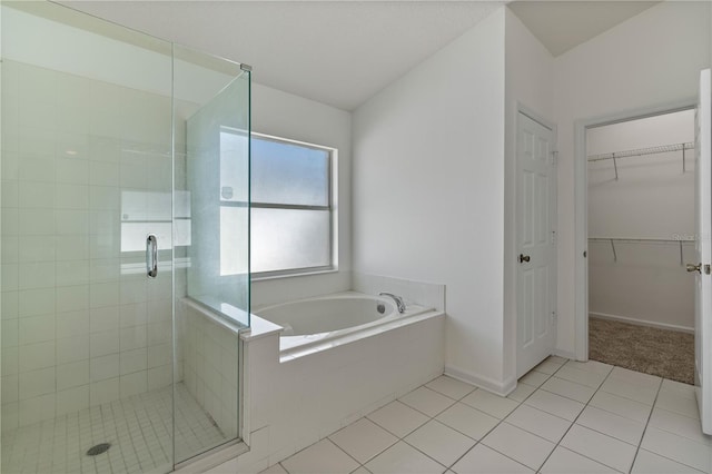 bathroom featuring tile patterned floors, a walk in closet, a shower stall, baseboards, and a bath