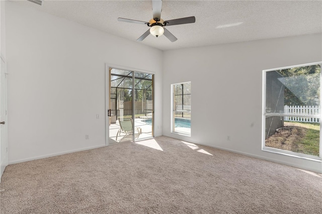 carpeted spare room featuring baseboards, a textured ceiling, a ceiling fan, and a sunroom