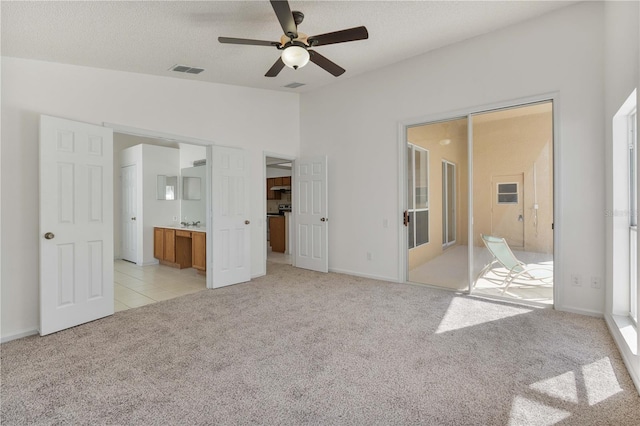 unfurnished bedroom with visible vents, light colored carpet, lofted ceiling, ensuite bathroom, and a textured ceiling