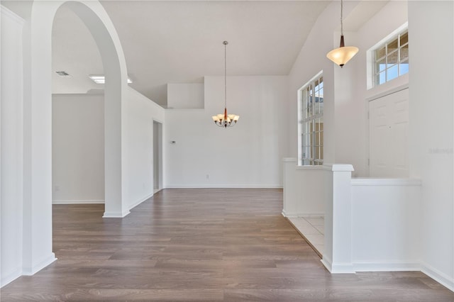 interior space featuring visible vents, baseboards, a notable chandelier, and wood finished floors