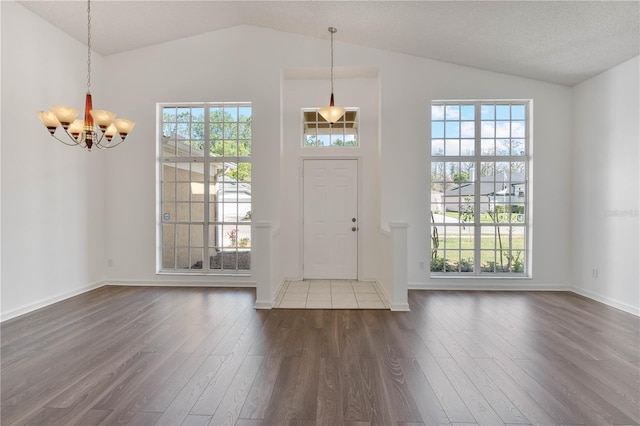 foyer featuring baseboards, dark wood-type flooring, an inviting chandelier, and high vaulted ceiling