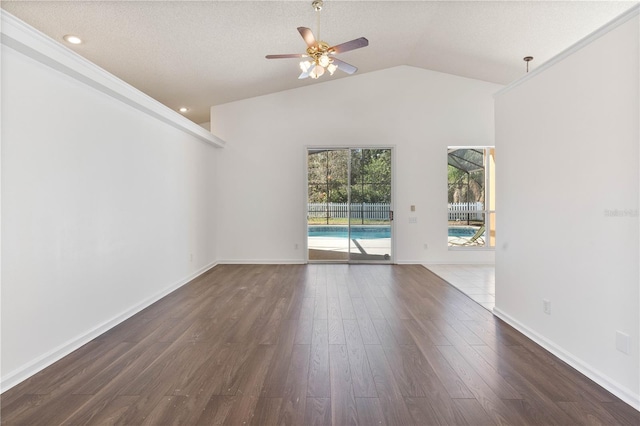 spare room featuring baseboards, vaulted ceiling, a textured ceiling, a ceiling fan, and dark wood-style flooring