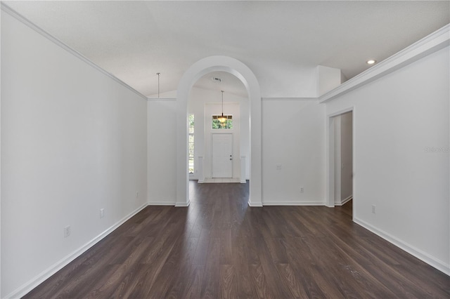 unfurnished room with arched walkways, lofted ceiling, baseboards, and dark wood-style flooring