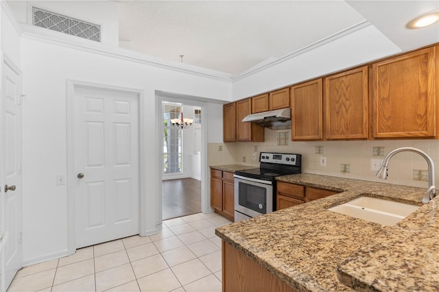 kitchen featuring visible vents, under cabinet range hood, stainless steel electric range, brown cabinetry, and a sink