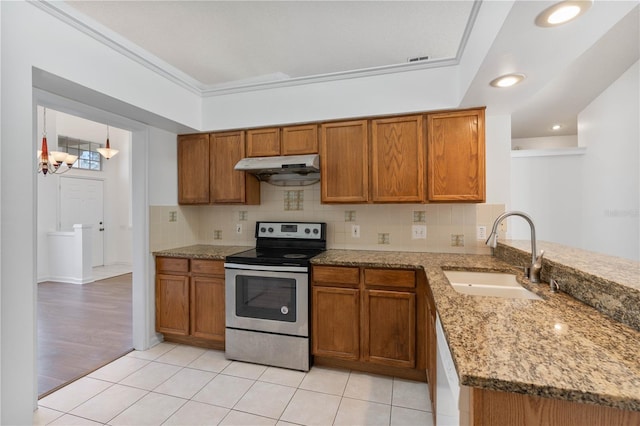 kitchen with brown cabinets, a sink, under cabinet range hood, backsplash, and stainless steel range with electric cooktop