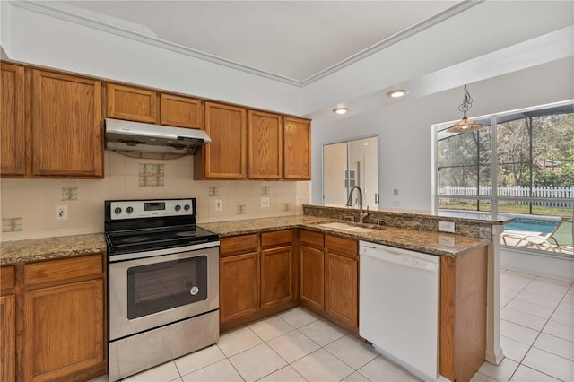 kitchen with under cabinet range hood, dishwasher, stainless steel range with electric cooktop, brown cabinetry, and a sink