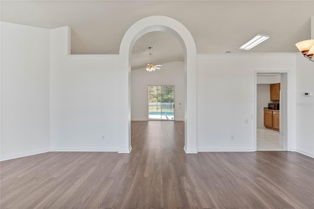 spare room with visible vents, baseboards, ceiling fan, wood finished floors, and arched walkways