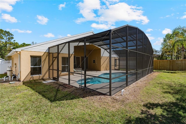 rear view of house with fence, a lanai, stucco siding, a yard, and a patio