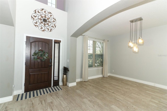 entryway with baseboards, arched walkways, and wood finished floors