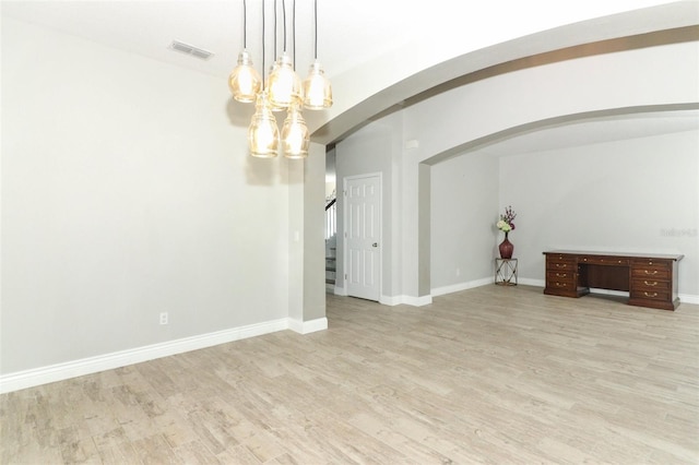 interior space with stairway, baseboards, visible vents, arched walkways, and light wood-type flooring