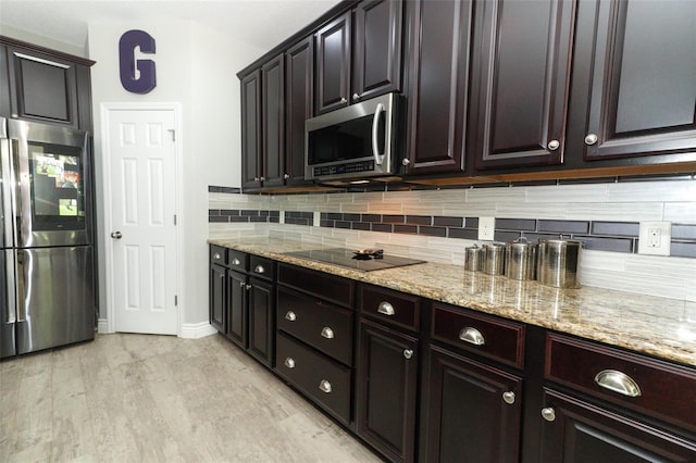 kitchen with light stone counters, stainless steel appliances, tasteful backsplash, and light wood-style flooring