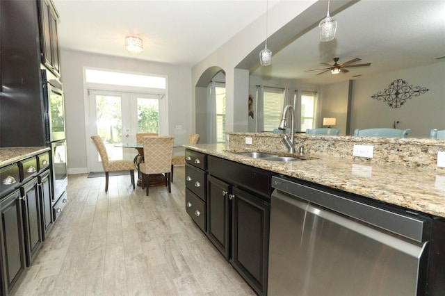 kitchen with decorative light fixtures, light wood-style flooring, french doors, stainless steel appliances, and a sink