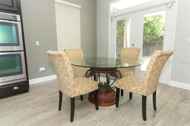 dining space with a healthy amount of sunlight, light wood-type flooring, french doors, and baseboards