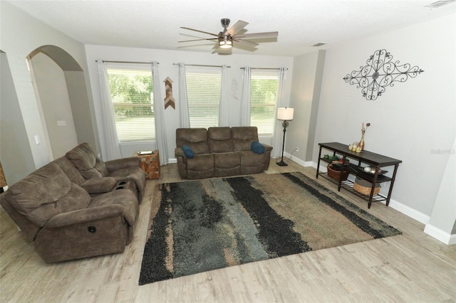 living room featuring a wealth of natural light, arched walkways, and wood finished floors