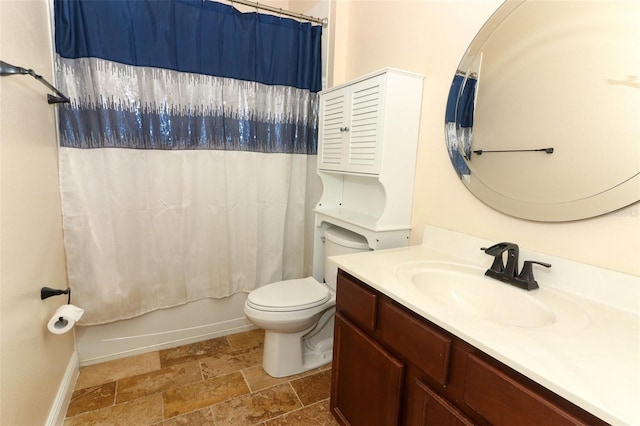 bathroom with vanity, stone tile floors, baseboards, toilet, and shower / tub combo with curtain