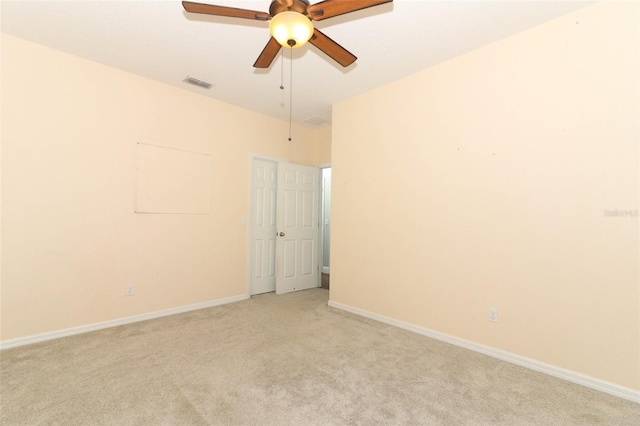 empty room with visible vents, light colored carpet, baseboards, and ceiling fan