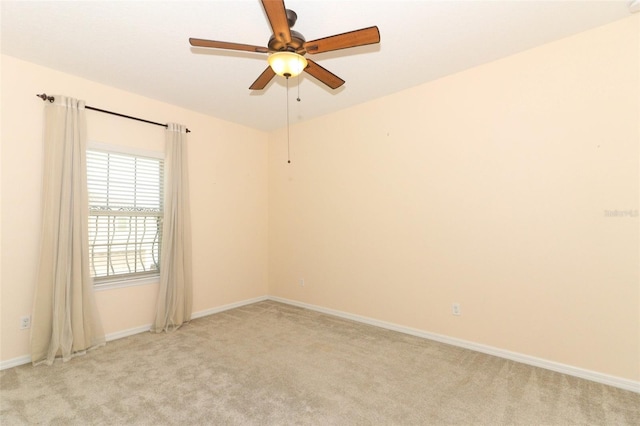 spare room featuring a ceiling fan, light colored carpet, and baseboards