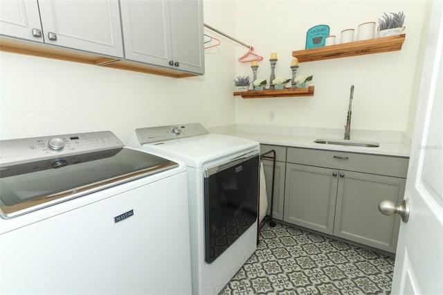 laundry room with washing machine and clothes dryer, cabinet space, bar, and a sink