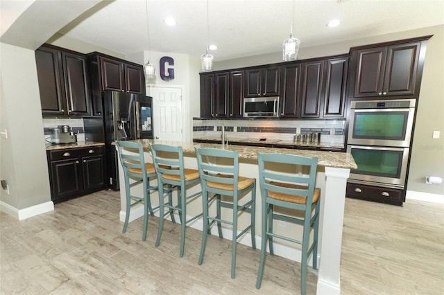 2351 Kelbrook Ct, Oviedo, FL 32765 - kitchen featuring appliances with stainless steel finishes, decorative backsplash, light wood-type flooring, decorative light fixtures, and a breakfast bar