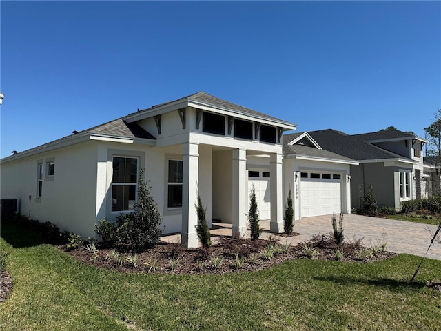 view of front of home featuring stucco siding, an attached garage, decorative driveway, and a front yard