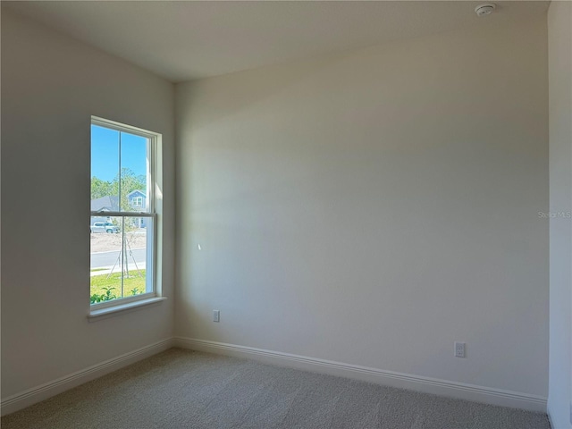 spare room with light carpet and baseboards