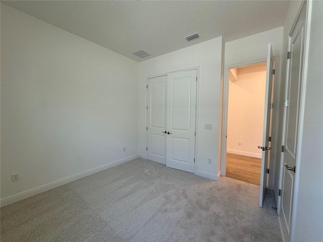 unfurnished bedroom featuring visible vents, carpet floors, baseboards, and a closet