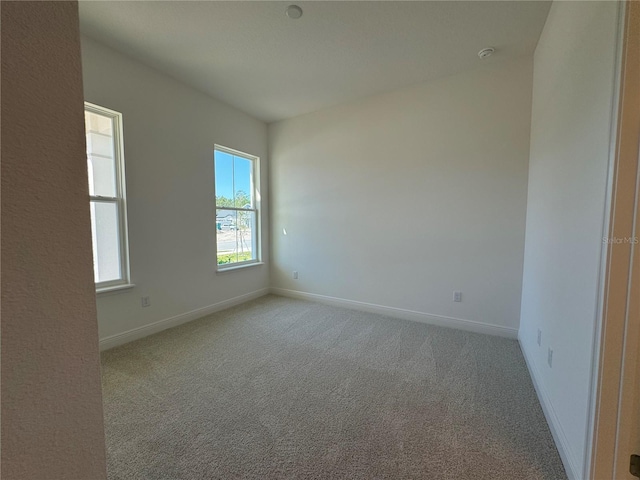 unfurnished room with carpet flooring and baseboards