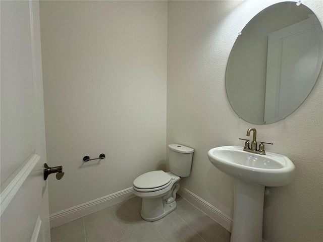 bathroom with tile patterned floors, toilet, baseboards, and a sink