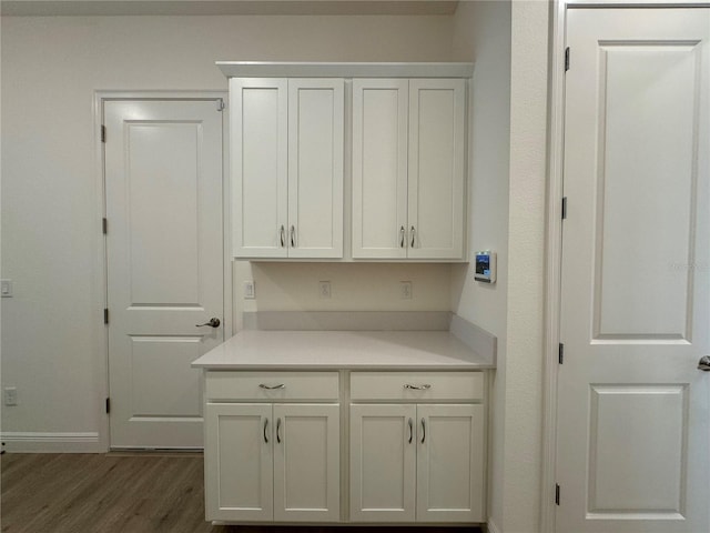 kitchen featuring light countertops, white cabinets, dark wood-style floors, and baseboards