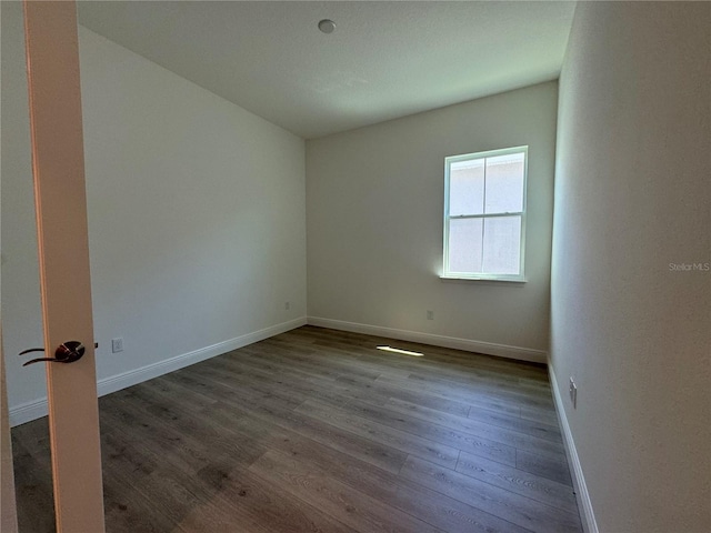 unfurnished room featuring dark wood-style floors and baseboards