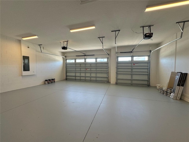 garage with concrete block wall, electric panel, and a garage door opener