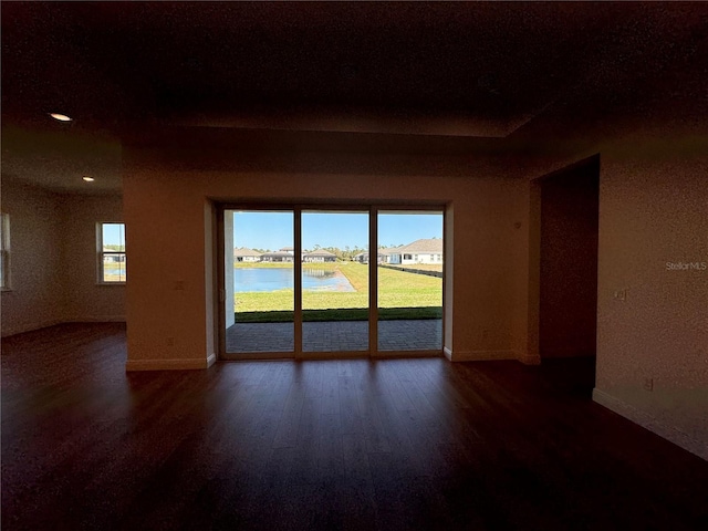 spare room featuring baseboards, wood finished floors, and a water view