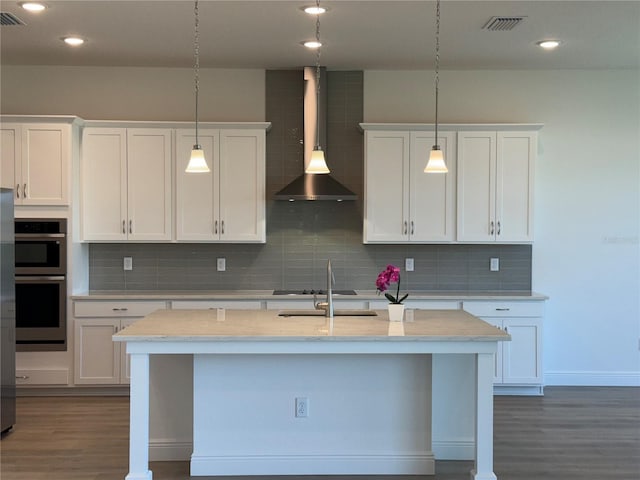 kitchen with white cabinetry, wall chimney range hood, dark wood-style flooring, and stainless steel double oven