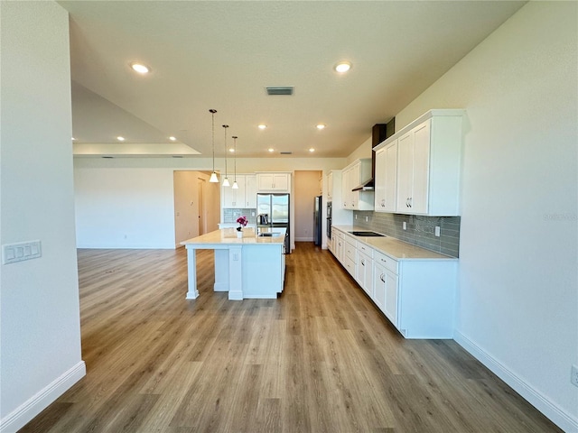 kitchen featuring visible vents, white cabinets, stainless steel fridge with ice dispenser, and tasteful backsplash